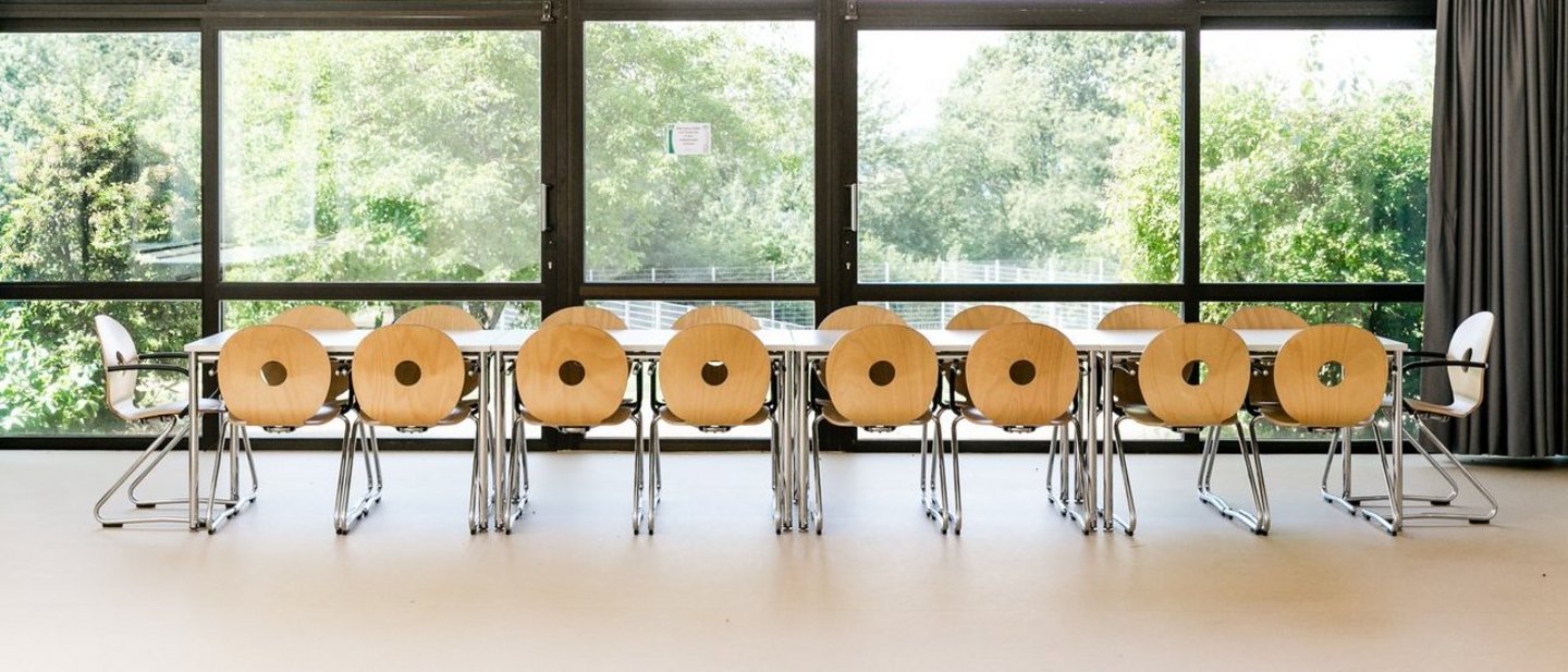 Großer heller lichtdurchfluteter Raum mit einem langen Tisch und Stühlen