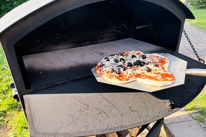 Pizzaofen in den eine belegte Pizza reingeschoben wird